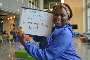 Photo of a student holding a sign that says she screams for the Earth because "someone has to!"