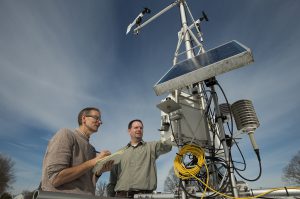 Two scientists inspect a solar-powered weather and climate observation instrument array