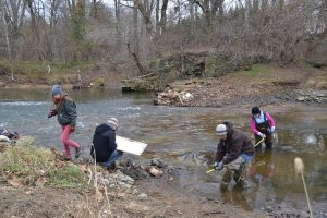 Students take measurements and sketch details of a low dam across a creak