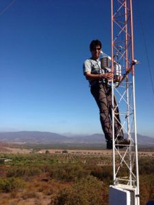 Photo of a scientist working with equipment high above ground on an instrument tower