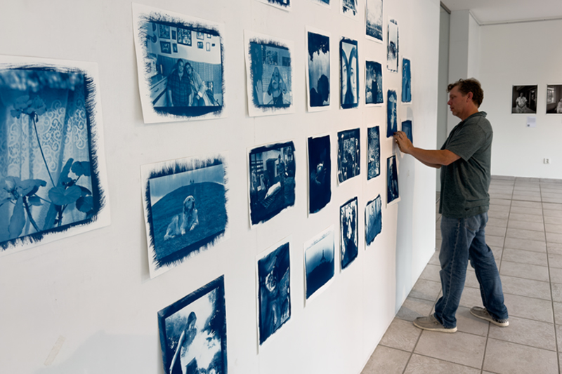 man standing in front of a wall of photographs