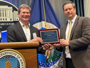 Two men standing behind a podium holding an award.